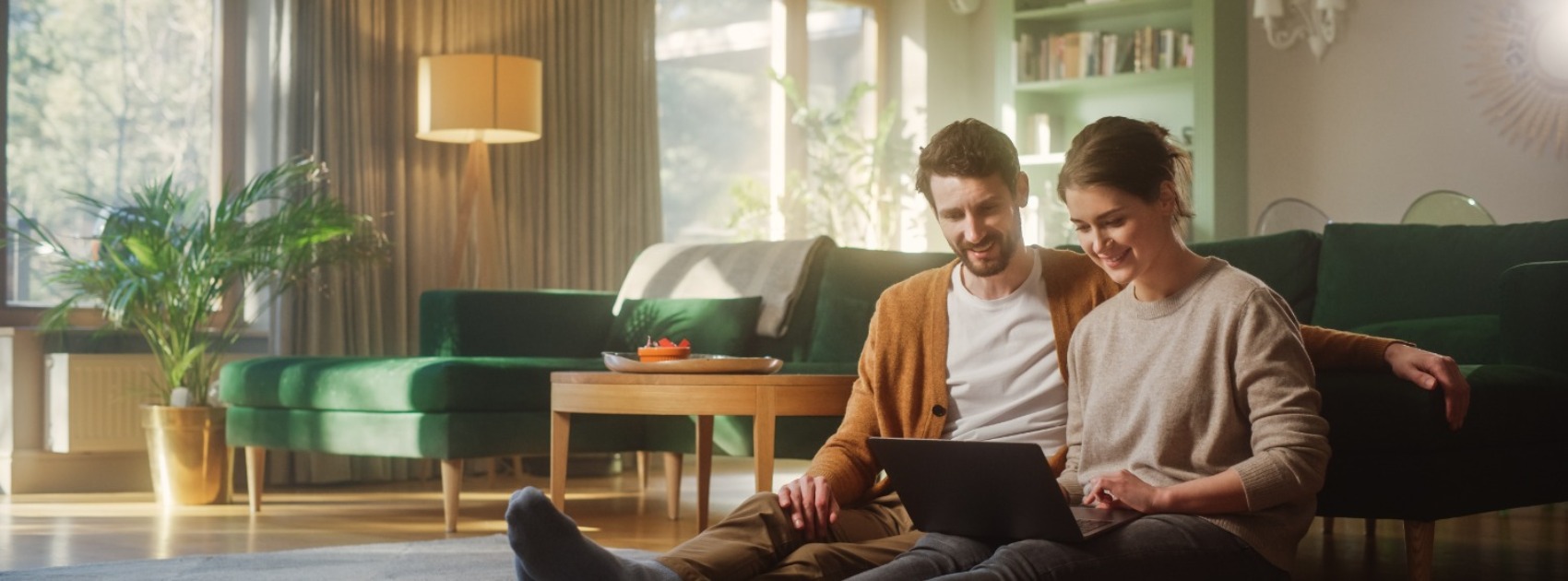 Happy couple sitting in living room and using a laptop computer